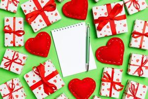 vakantie samenstelling van notitieboekje, geschenk dozen en rood textiel harten Aan kleurrijk achtergrond met leeg ruimte voor uw ontwerp. top visie van Valentijnsdag dag concept
