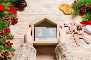 top visie van vrouw handen Holding een kalender Aan houten achtergrond. de twintig vijfde van december. vakantie decoraties. Kerstmis concept foto