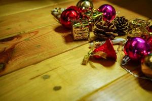 nieuw jaar en Kerstmis geschenk themed decoraties Aan houten achtergrond, bestaande van een gouden geschenk doos. glimmend gekleurde ballen droog pijnboom kegels en klein klokken vrij ruimte voor ontwerp foto