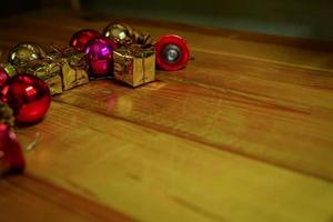 nieuw jaar en Kerstmis geschenk themed decoraties Aan houten achtergrond, bestaande van een gouden geschenk doos. glimmend gekleurde ballen droog pijnboom kegels en klein klokken vrij ruimte voor ontwerp foto