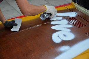 Charkov, Oekraïne - mei 27, 2022 festival van straat kunst. jong jongens trek graffiti Aan de auto lichaam in de stad centrum. de werkwijze van tekening kleur graffiti Aan een auto met aërosol blikjes foto