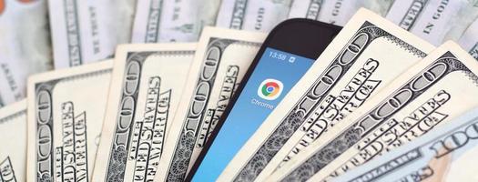 Charkov, Oekraïne - mei 12, 2022 smartphone scherm met google chroom app en veel van honderd dollar rekeningen. bedrijf en sociaal netwerken concept foto