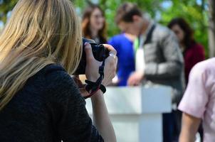 bruiloft fotograaf in de werkwijze van zijn werk. professioneel fotograaf schiet een bruiloft ceremonie. een jong meisje looks in de camera's zoeker foto