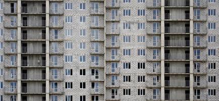 getextureerde patroon van een Russisch witte steen woon- huis gebouw muur met veel ramen en balkon onder bouw foto