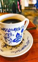 blauw wit kop pot met zwart koffie houten tafel Mexico. foto