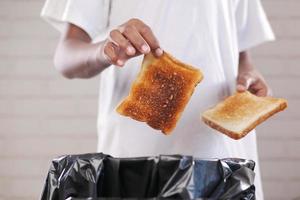mannen het werpen een brood in een vuilnis bak foto