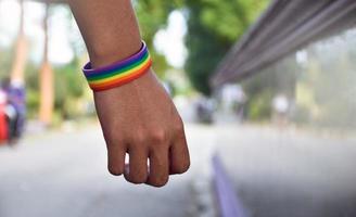 regenboog polsbandje vervelend in hand- van jong Aziatisch homo naar tonen en staan voor geslacht diversiteit, naar respect menselijk rechten in alternatief seks, naar hou op straffen homoseksuelen in sommige religies foto