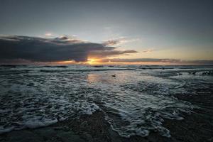 zonsondergang Aan de strand in Denemarken. golven Aan de zand. wandelen Aan de kust in de zand foto