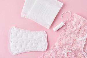 sanitair kussen, menstruatie- beker, tampon en slipje Aan een roze achtergrond foto