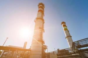 gas- turbine macht fabriek Aan natuurlijk gas- met schoorstenen van rood Wit kleur tegen een blauw lucht Aan een zonnig dag foto