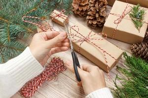 Kerstmis geschenk omhulsel achtergrond. vrouw handen verpakking Kerstmis Cadeau verpakt in kraft papier top visie. winter vakantie concept vlak leggen vrouw Holding Kerstmis geschenk doos foto