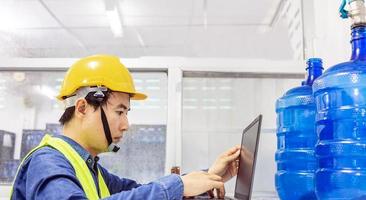 ingenieur werken in drinken water fabriek gebruik makend van een tablet computer naar controleren en reparatie boiler water naar de water systeem in fabriek foto