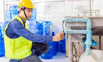 ingenieur werken in drinken water fabriek gebruik makend van een tablet computer naar controleren en reparatie boiler water naar de water systeem in fabriek foto