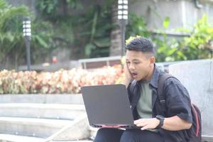 aantrekkelijk jong Aziatisch Mens gebruik makend van laptop verward in samenwerken ruimte met ongelukkig gezicht foto