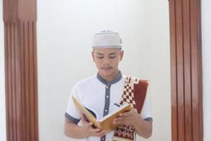 jong Aziatisch moslim bidden in de moskee draag- een gebed mat foto