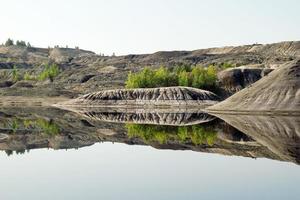 visie Aan een overstroomd steengroeve met reflectie van heuvels en bomen. foto