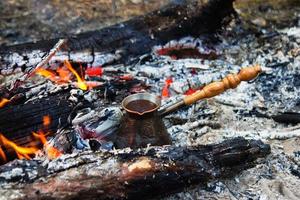 metaal cezve met heet gearomatiseerd koffie Aan een vreugdevuur. foto