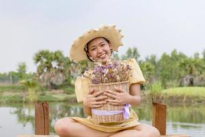 geluk, een mooi vrouw in de tuin, geplaatst in een hoed, Holding bloemen. foto