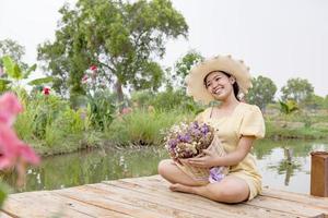 geluk, een mooi vrouw in de tuin, geplaatst in een hoed, Holding bloemen. foto