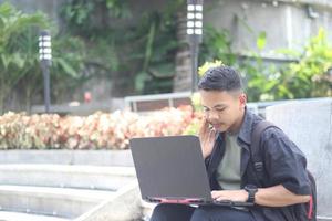 aantrekkelijk jong Aziatisch Mens gebruik makend van laptop in samenwerken ruimte met gelukkig gezicht foto