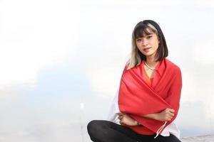 mooi jong Aziatisch vrouw draag- de Indonesisch vlag met een vrolijk gezicht foto