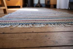 veelkleurig tapijt Aan een houten vloer, achtergrond afbeelding. kopiëren ruimte foto