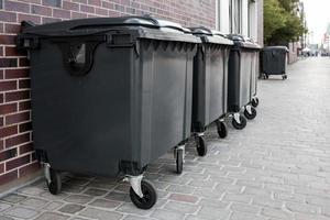 meerdere nieuw grijs plastic afvalcontainer staan in de buurt de steen muur van de gebouw, Aan een stad straat. foto