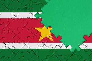 Suriname vlag is afgebeeld Aan een voltooid decoupeerzaag puzzel met vrij groen kopiëren ruimte Aan de Rechtsaf kant foto