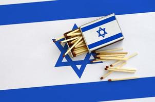 Israël vlag is getoond Aan een Open luciferdoosje, van welke meerdere wedstrijden vallen en leugens Aan een groot vlag foto
