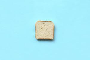 een stuk van brood leugens Aan structuur achtergrond van mode pastel blauw kleur papier in minimaal concept foto