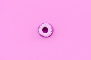 single klein plastic donut leugens Aan een pastel kleurrijk achtergrond. vlak leggen minimaal samenstelling. top visie foto