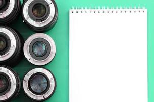 meerdere fotografisch lenzen en wit notitieboekje liggen Aan een helder turkoois achtergrond. kopiëren ruimte foto