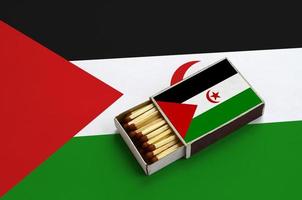 western Sahara vlag is getoond in een Open luciferdoosje, welke is gevulde met wedstrijden en leugens Aan een groot vlag foto