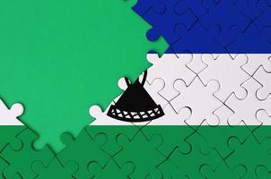 Lesotho vlag is afgebeeld Aan een voltooid decoupeerzaag puzzel met vrij groen kopiëren ruimte Aan de links kant foto