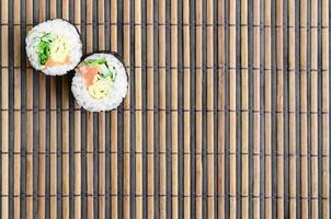 sushi broodjes leugens Aan een bamboe rietje naaien mat. traditioneel Aziatisch voedsel. top visie. vlak leggen minimalisme schot met kopiëren ruimte foto