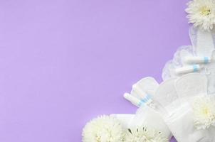 menstruatie- stootkussens en tampons met inschrijving wit bloemen Aan pastel lila achtergrond foto