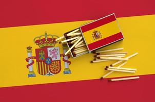 Spanje vlag is getoond Aan een Open luciferdoosje, van welke meerdere wedstrijden vallen en leugens Aan een groot vlag foto