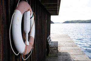 reddingsboei blijft hangen Aan een oud houten hut Aan de pier, tegen de backdrop van een mooi landschap van de zee en rotsen. concept van een veilig vakantie. foto