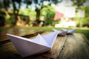 origami, wit papier boot geïsoleerd Aan een houten vloer. papier boten gemeen wandelen. gevoel van vrijheid leiderschap foto