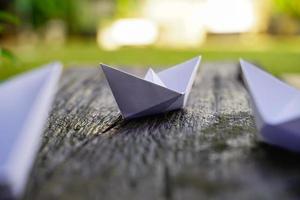 origami, wit papier boot geïsoleerd Aan een houten vloer. papier boten gemeen wandelen. gevoel van vrijheid leiderschap foto