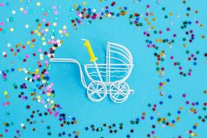een jaar verjaardag.baby wandelwagen met kaars in het formulier van de aantal een Aan een blauw achtergrond met sterren confetti pailletten foto