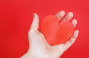 vrouw handen houden een rood hart Aan de palmen geïsoleerd Aan een rood achtergrond. liefde, bruiloft, valentijnsdag dag, 8 maart concept. foto