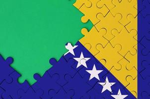 Bosnië en herzegovina vlag is afgebeeld Aan een voltooid decoupeerzaag puzzel met vrij groen kopiëren ruimte Aan de links kant foto
