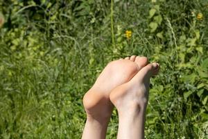 blootsvoets vrouw voeten koesteren in de zon Aan een heet zomer dag, tegen de backdrop van groen. vakantie concept. foto