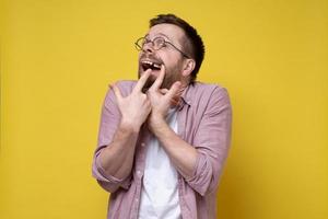 Mens in bril en gewoontjes kleren geopend zijn mond en shows een missend tand met vingers. foto