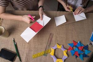 mam en dochter maken origami van gekleurde papier Aan zelfisolatie foto