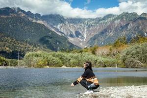 Aziatisch meisje met een mooi achtergrond van centrum kamikochi nationaal park door sneeuw berg, rots en azusa rivier- van heuvel Hoes met blad verandering kleur gedurende vallen gebladerte seizoen. foto