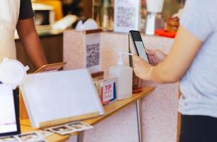 Aziatisch klant Dames betalen door qr code scannen Aan mobiel telefoon Bij koffie winkel. foto