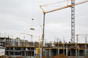 bouw van groot modern monolithisch kader huizen, gebouwen gebruik makend van industrieel bouw uitrusting en groot hoog kranen. bouw van de gebouw in de nieuw micro wijk van de stad foto