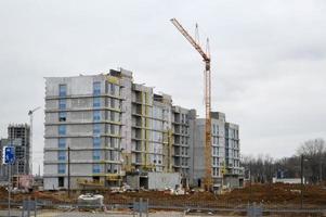 bouw van een nieuw microdistrict met hoog huizen, nieuw gebouwen met ontwikkelde infrastructuur met de helpen van groot industrieel kranen en professioneel bouw uitrusting in een groot stad foto